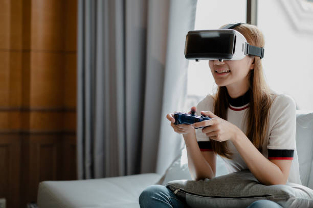istock Women wearing virtual reality glasses and game joystick to play games, using virtual reality technology to facilitate and enjoy relaxation, boundless imagination, Smartphone using with VR headsets. 1394888855