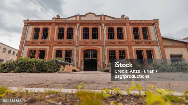 Old Industrial Warehouse In Kragujevac Serbia Made Of Red Bricks Ruined Windows And Deserted Interior On A Cloudy Day With Cannons On The Entrance Stock Photo - Download Image Now