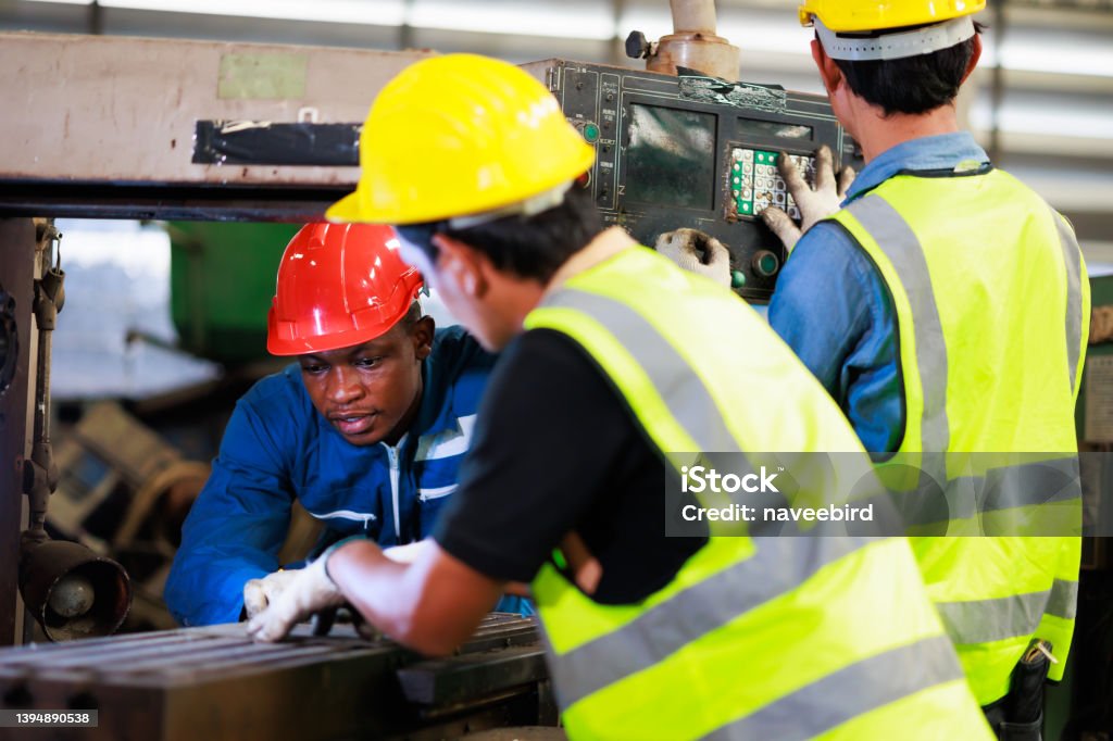 Training trainee concept. Yang male african american engineer explain the procedure for using the correct metal machine at factory. Trainee Stock Photo
