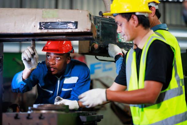 istock Training trainee concept. Yang male african american engineer explain the procedure for using the correct metal machine at factory. 1394890539
