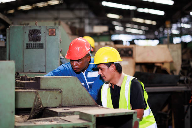 istock Training trainee concept. Yang male african american engineer explain the procedure for using the correct metal machine at factory. 1394890544