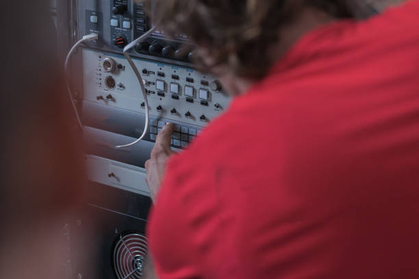 istock Person in red shirt pressing a button on a video switch panel or hub. High technology environment with a person operating a button. 1394890700