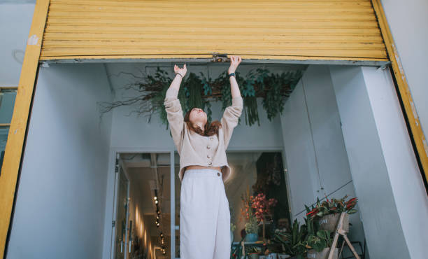 asiatica cinese femmina fiorista fiorista proprietario di negozio di fiori spingendo su griglia di metallo cancello aperto per affari - store opening foto e immagini stock