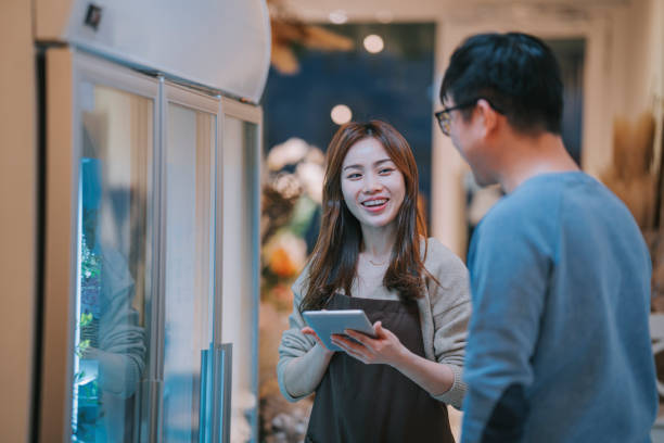 istock Asian Chinese female florist explaining to customer on variant flower package selection from refrigerator 1394891576
