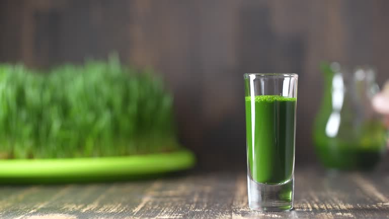 Green leaves of young wheat and wheatgrass juice pouring into a glass