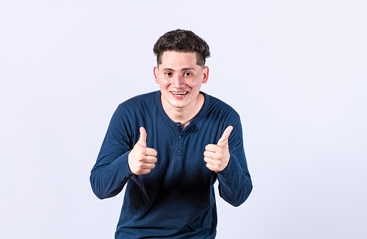 Positive guy with thumbs up doing ok, young man with thumbs up on white background, Smiling man showing ok gesture looking at camera