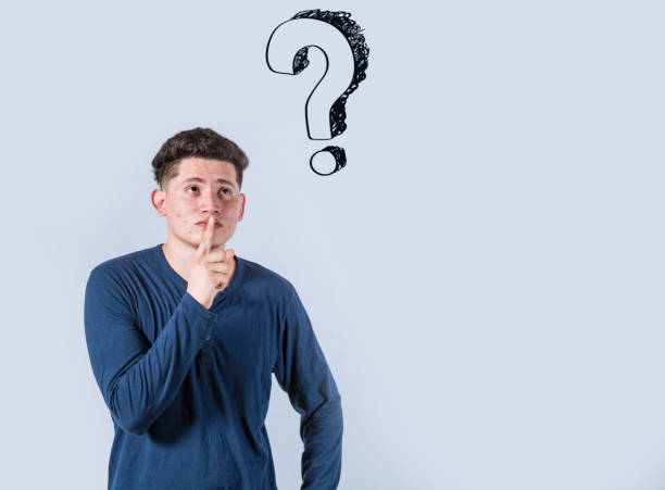 istock Thoughtful young man looking up with exclamation marks, Thoughtful man with exclamation marks on isolated background, Indecisive man looking up , Concept of man asking with exclamation marks