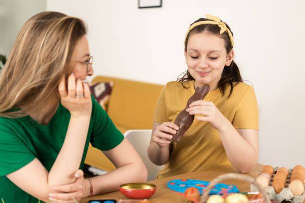 istock Girl enjoying a chocolate bunny while painting Easter eggs with her mom 1394896750