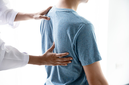 Female doctor and patient back pain after exercise in medical clinic.