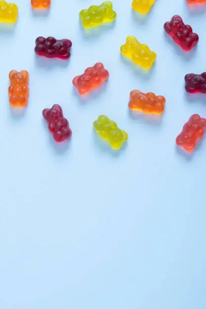 Colored jelly bears on a pastel blue background. Top view.