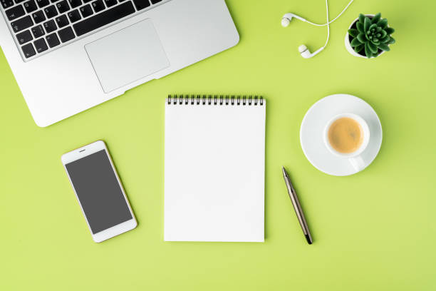Concept of modern workspace. Notebook, smartphone, coffee cup, laptop and earphones on green backdrop stock photo