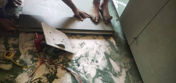 istock Work In progress -  A carpenter's work at a construction site with circular electrical saw machine, 
 along with green coloured wooden board, sawdust scattered in messy way and a person's bare feet and hands on plank near the wires and machinery 1394902299