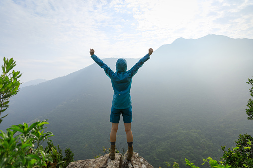 Successful woman outstretched limbs on summer sunrise mountain top
