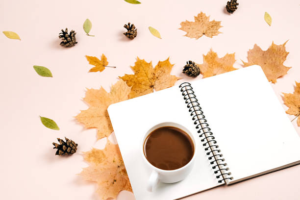 istock Autumn flat lay with dry leaves, notebook, pine cone and coffee cup on pastel beige background in studio with copy space for advertisement. Thanksgiving, fall, halloween concept. Creative composition 1394904101