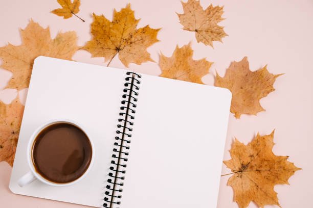 istock Flat lay composition with dry maple leaves, notebook and coffee latte cup on pink color background wall in studio. Creative autumn, thanksgiving, fall, halloween concept. Top view, copy space 1394904105