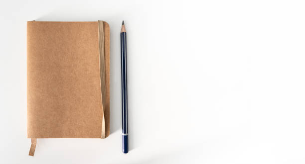 istock small notebook and pencil on white desk 1394906466