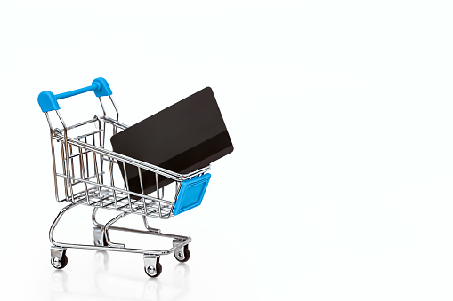 Online shopping concept: shopping cart with a bank card, isolated on a white background