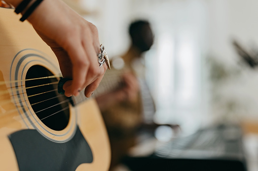 Close up photo of woman wearing jewellery and playing guitar