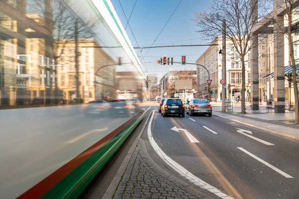 Magdeburg, downtown district Magdeburg, Sachsen-Anhalt, Germany - 03 24 2022, streetcar crosses the intersection while cars stop at the traffic light in downtown district on a spring day blurred motion street car green stock pictures, royalty-free photos & images