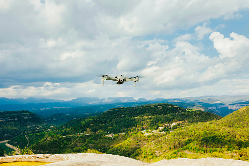 Drone copter with digital camera, at top of mountain, river on background. Modern technology, UAV concept.