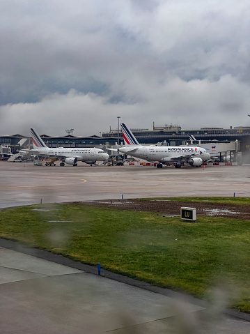 Paris, France, 04/08/2022; View from Aircraft window on terminal building of Roissy Charles de Gaulle International Airport. Rainy cloudy grey day. Rain drops on window. Selective focus.  Commercial civil airplanes parking outside