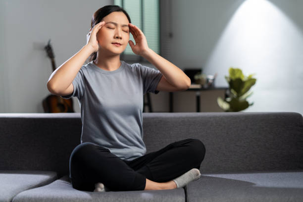 Asian woman was sick with headache. Asian woman using hands massage her head was sick with headache sitting on sofa in living room at home. long covid stock pictures, royalty-free photos & images