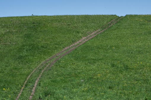 Rural road going up a grassy hill. Path to the sky.