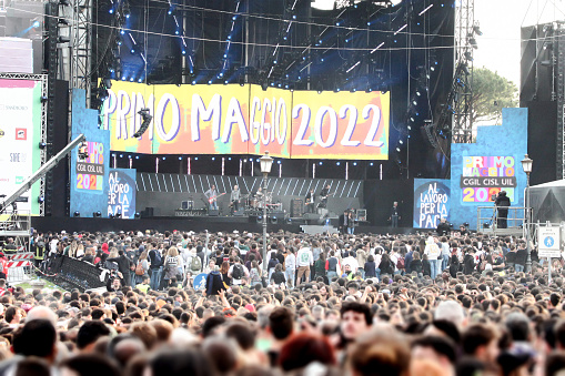 Large crowd of young people standing in front of a stage while artists play music. May 1st concert is a popular outdoor event held every year in Rome, Italy, in Piazza San Giovanni.