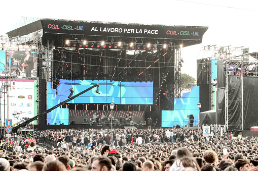 May 1st concert stage in Rome, Italy, with large crowd of young people filling a central city square. May 1st concert is a popular outdoor event held every year in Rome, Italy, in Piazza San Giovanni.