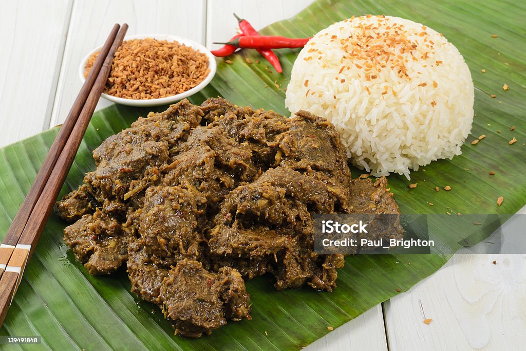 Beef Rendang &amp; Sticky Rice Malaysian spicy dry beef stew with coconut and sticky rice served on a banana leaf. Rendang Stock Photo