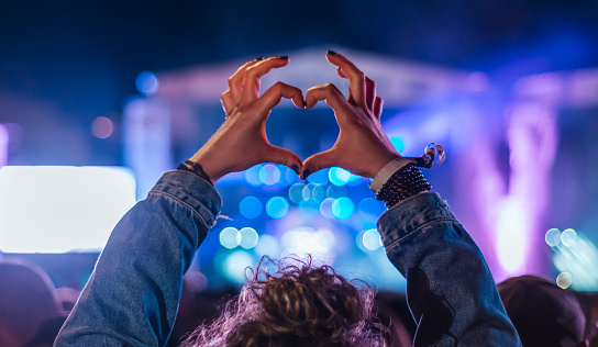 Woman making heart shape with hands at music event