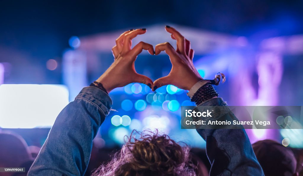 Woman making heart shape with hands at music event Music Festival Stock Photo