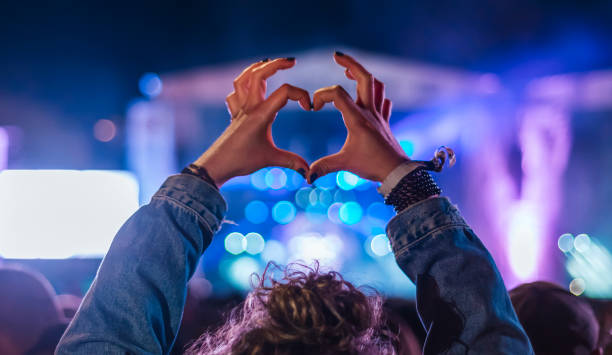 Woman making heart shape with hands at music event stock photo
