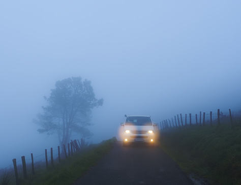Car with lights on a foggy mountain road, mount Jaizkibel, Euskadi