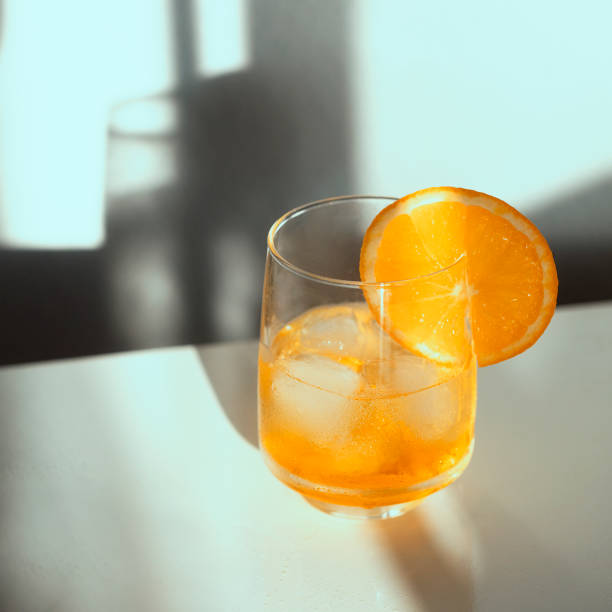 istock Alcohol cocktail with ice cubes on white background with hard light and shadow. Toned. Summer time and vacation concept. 1394920508