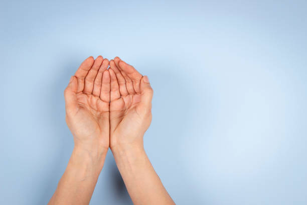 istock Empty cupped palm hands, keeping hands together on light blue background. Top view to outstretched woman hands. Care, help, support, charity, donation concept 1394921504