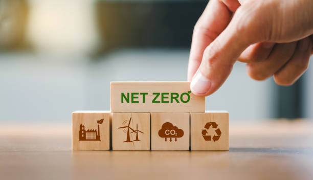 Close up hand put wooden cubes with green net zero icon and brown icon on wooden background.Net zero and carbon neutral concept. Net zero greenhouse gas emissions target. stock photo