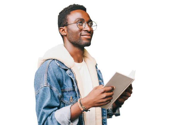 Portrait of young african man student with book looking away wearing eyeglasses isolated on white background stock photo