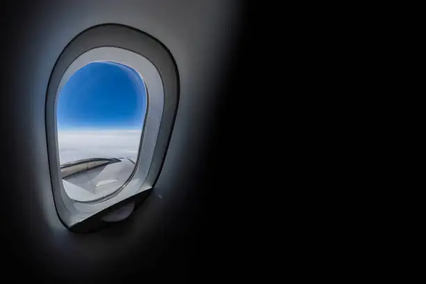 View from airplane window and air travel concept: Looking out aircraft bull's eye. Beautiful scenery from the air through plane porthole. Black background with copy space. Usable for tourism theme web banners, brochures, template or poster. Flying high over the sky