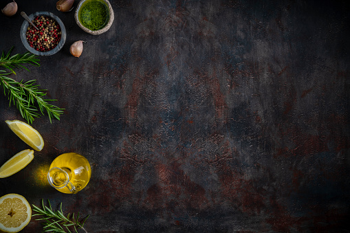Food copy space background with lemoin, olive oil, pepper, garlic rosmery and sauce on dark moody gray