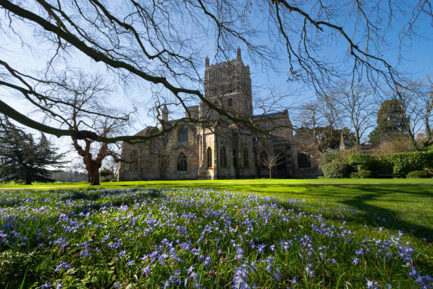 abadía de tewkesbury en azul con una abundancia de flores y cielos azules. - tewkesbury abbey fotografías e imágenes de stock