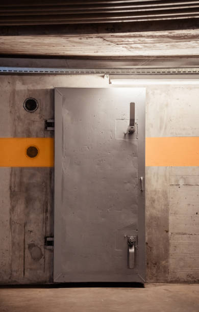 Thick metal hermetic door enter into nuclear fallout shelter built in basement of building for case of atomic attack stock photo