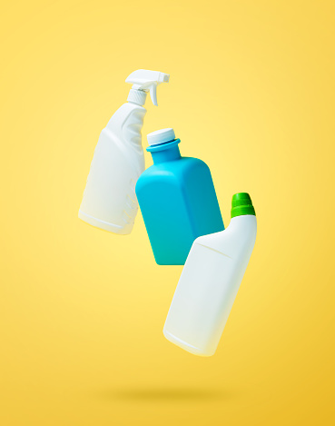 Levitation, falling in air blank household chemical bottles for cleaning the house. Isolated on yellow background. Plastic packaging. Toilet cleaner, detergent sprayer, soap. New brand product mockup