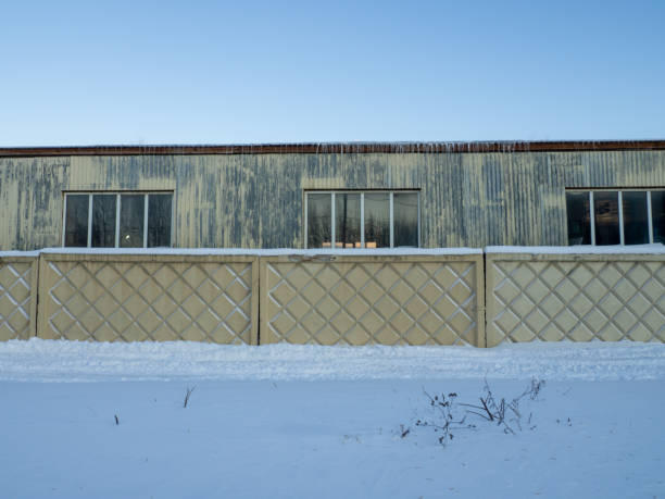 istock Old warehouse. Fence and old warehouse assignment. Industrial zone. Icicles on the roof. 1394929952