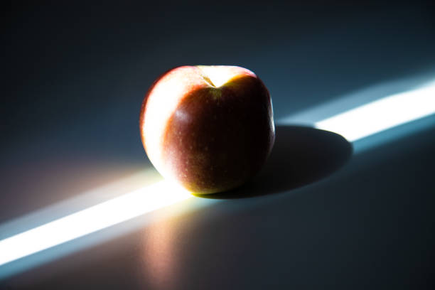 An apple on a table in a beam of bright light