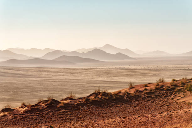 typical red dune in the foreground of namib rand nature reserve with mountain ranges in the background
