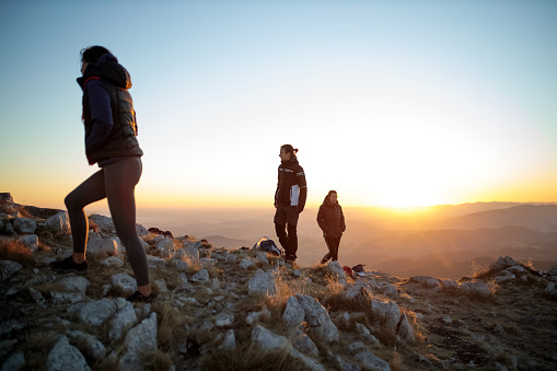 Small group of female mountain climbers spending time on top of the Rtanj mountain at sunrise, preparing to hike down
