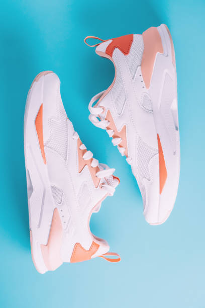 istock White women's sneakers with coral inserts on blue background. Top view, flat lay. 1394934554