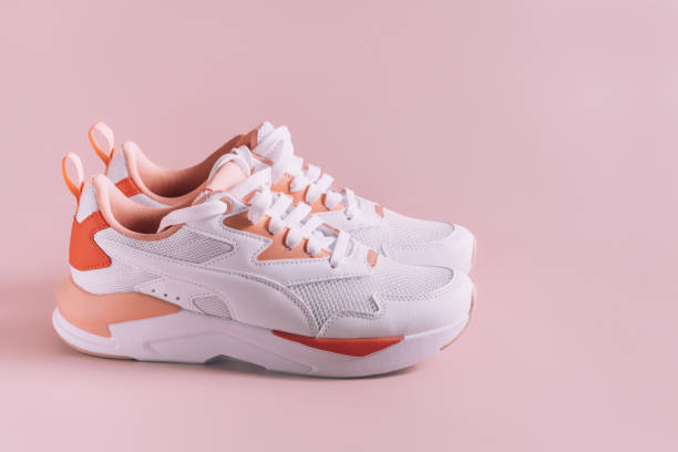 istock White women's sneakers with coral inserts, on pink background 1394934574