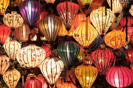 Close-Up Of Illuminated Lanterns Hanging At Night. Magical Chinese multicoloured lamps in an outdoor store. Traditional silk lanterns in night market. Hoi An city, Vietnam